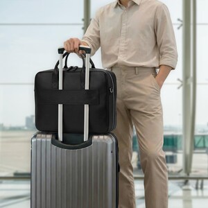 May include: A black leather briefcase with dual top handles and a horizontal strap on the back, positioned on top of a silver metallic rolling suitcase with vertical ridges. The briefcase features a zippered closure and silver hardware accents.