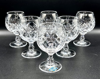 May include: Set of six clear crystal glasses with a cut glass design. The glasses have a round bowl and a short stem.