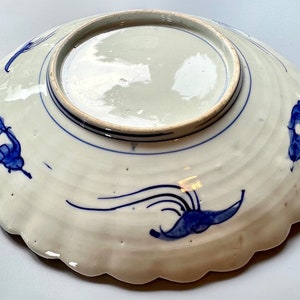 K&ouml;nnte beinhalten: Ein wei&szlig;er Teller aus Keramik mit einem blauen und wei&szlig;en Blumendesign. Der Teller hat einen gewellten Rand und ist mit einem blauen und wei&szlig;en Blumendesign verziert.