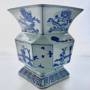 Puede incluir: Un jarr&oacute;n de porcelana azul y blanco con forma hexagonal y un dise&ntilde;o geom&eacute;trico alrededor de la base. El jarr&oacute;n presenta un drag&oacute;n y otras figuras en un estilo chino tradicional.