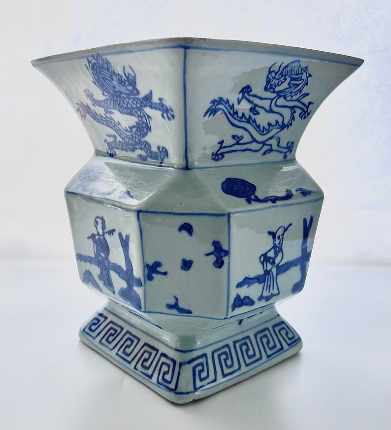 Puede incluir: Un jarr&oacute;n de porcelana azul y blanco con forma hexagonal y un dise&ntilde;o geom&eacute;trico alrededor de la base. El jarr&oacute;n presenta un drag&oacute;n y otras figuras en un estilo chino tradicional.