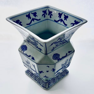 Puede incluir: Un jarr&oacute;n de porcelana azul y blanco con base cuadrada y dise&ntilde;o geom&eacute;trico. El jarr&oacute;n presenta un patr&oacute;n chino tradicional con figuras y &aacute;rboles.