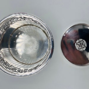 May include: Silver round box with a decorative design on the side and a lid with a Celtic knot design.