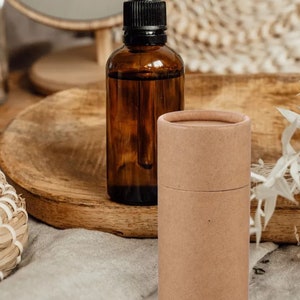 May include: A brown glass bottle with a dropper and a brown cardboard tube. The bottle and tube are sitting on a wooden surface.