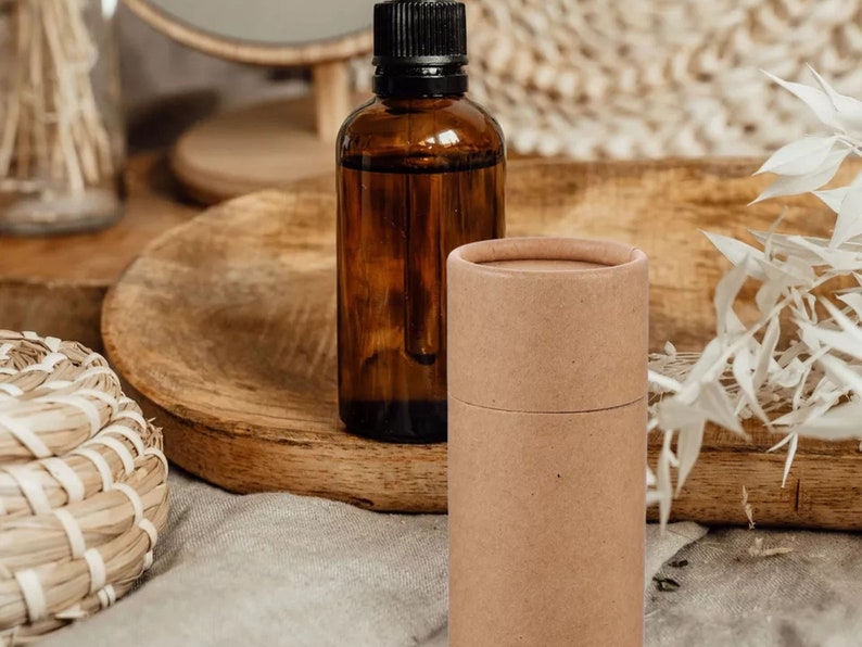 May include: A brown glass bottle with a dropper and a brown cardboard tube. The bottle and tube are sitting on a wooden surface.