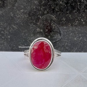 Puede incluir: Un anillo de plata con una gran piedra preciosa roja ovalada, engastada en un sencillo engaste de bisel de plata.