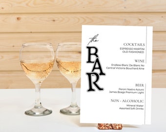 Puede incluir: Un cartel blanco con texto negro que dice "the BAR" y enumera cócteles, vino, cerveza y bebidas no alcohólicas. El cartel está sobre un posavasos de corcho.