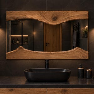 May include: A rectangular wall mirror featuring a natural live edge wood frame with a prominent wood grain and knot. The mirror is positioned above a matte black oval vessel sink, which sits on a dark countertop with a matching black faucet.