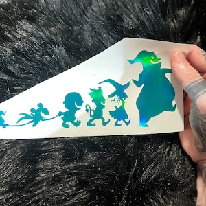 May include: A vinyl decal sheet featuring a series of iridescent, holographic silhouettes of characters from The Nightmare Before Christmas, including a duck on wheels, a bat-like creature, a small child, a devil, a witch, and a large ghost.