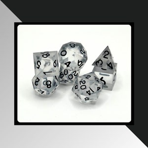 May include: Five clear, translucent dice with black numbers. The dice are in various shapes, including a standard cube, a pyramid, and a d20.