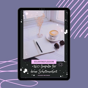 Puede incluir: Una pantalla de tableta que muestra un gráfico en blanco y negro con el texto "SELBSTREFLEKTION +160 Impulse für deine Schattenarbeit GALAXIE DER MAGIE". El gráfico está sobre un fondo blanco con puntos negros. La tableta está sobre una mesa con un cuaderno, un bolígrafo, una taza de café y un pequeño ramo de flores secas.