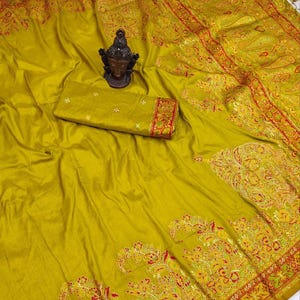 May include: A mustard yellow saree with a paisley pattern and gold and red embroidery. The saree has a decorative border with a floral design.