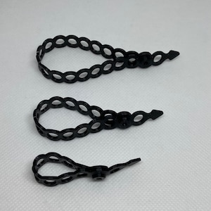 May include: Three black plastic cable ties with a series of small loops and a pointed end.