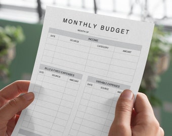 May include: A person is reviewing a monthly budget planner with sections for income, bills and fixed expenses, variable expenses, and a summary. The planner has columns for date, source, category, and amount.