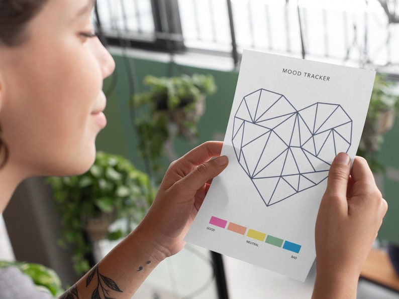 May include: A white mood tracker with a geometric heart design in blue. The heart is divided into sections with a color scale for tracking mood: good, neutral, and bad.