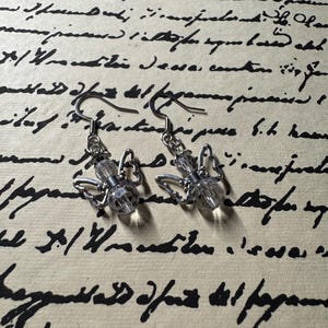 May include: A pair of silver dangle earrings with clear crystal butterfly charms.