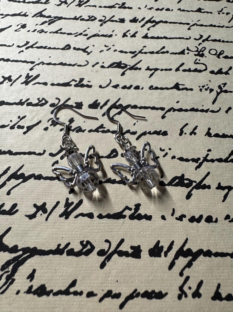 May include: A pair of silver dangle earrings with clear crystal butterfly charms.