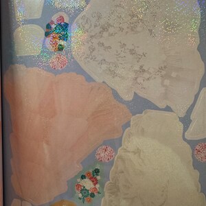 May include: A selection of iridescent stickers featuring diverse shapes and designs, such as floral arrangements, crowns, and abstract forms. The stickers have a shimmering, glittery effect and are set against a light blue backdrop. The text "Absolutely Enchanting: Pages 8-9" is visible.