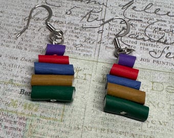May include: A pair of earrings made of polymer clay. Each earring is a stack of five colorful cylinders, with the colors purple, red, brown, green, and white. The earrings are hanging from silver hooks.