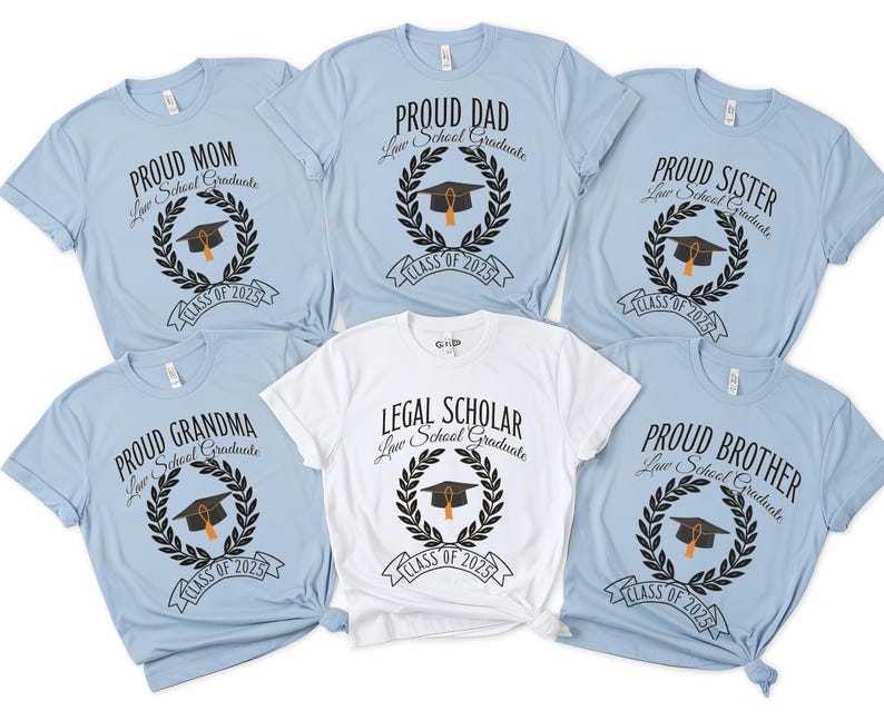 May include: Six light blue t-shirts with black text and graphics. The shirts say "Proud Mom", "Proud Grandma", "Proud Dad", "Proud Sister", "Proud Brother", and "Legal Scholar". Each shirt has a laurel wreath with a graduation cap and the text "Law School Graduate" and "Class of 2023".