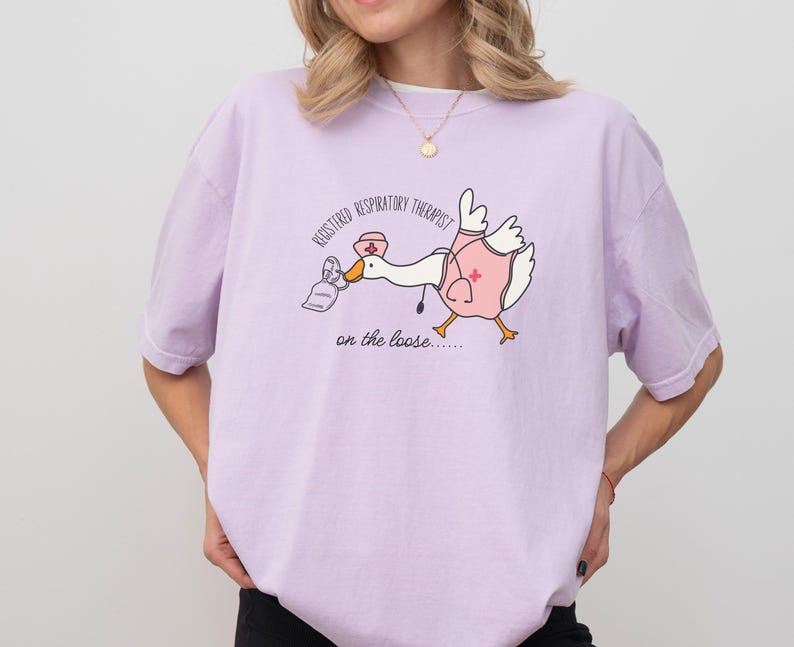 May include: A light purple t-shirt with a cartoon illustration of a goose wearing a nurse's hat and carrying a bag of medical supplies. The text "Registered Respiratory Therapist on the loose..." is printed on the shirt.