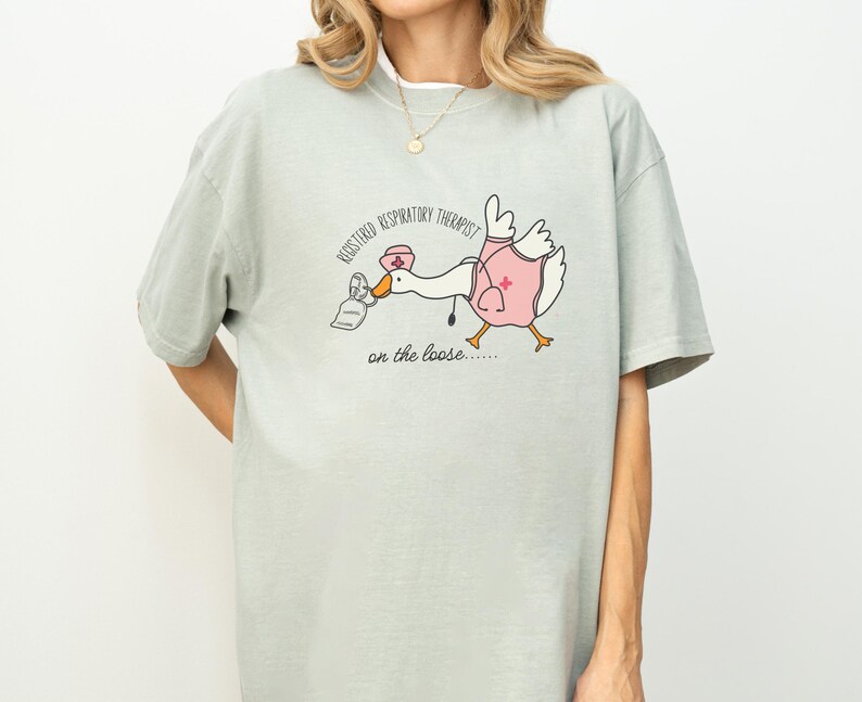 May include: A light green t-shirt with a cartoon goose wearing a nurse's hat and holding a nebulizer. The text on the shirt reads "Registered Respiratory Therapist on the loose..."
