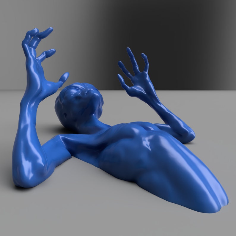 Puede incluir: Una escultura azul brillante de una figura humanoide tumbada sobre una superficie gris. Los brazos de la figura est&aacute;n extendidos, con las manos abiertas. La cabeza est&aacute; vuelta hacia arriba. La escultura tiene una superficie lisa y reflectante.
