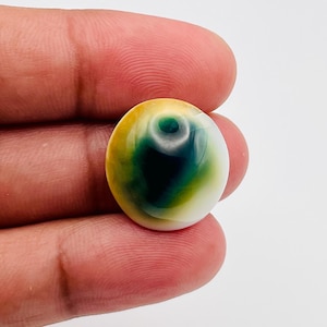 May include: A round, smooth cabochon gemstone featuring a gradient of colors transitioning from a deep, dark green center to a vibrant yellow-green midsection, ending in a crisp white outer edge with a polished, reflective surface finish.