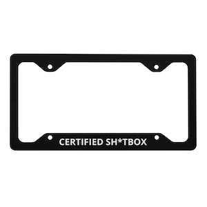 Puede incluir: Marco de matrícula negro con el texto "CERTIFIED SH*TBOX" en blanco. El marco tiene forma rectangular con esquinas redondeadas y cuatro orificios de montaje.