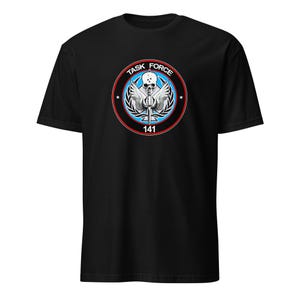 May include: Black t-shirt featuring a circular emblem with the text "TASK FORCE" at the top. The emblem includes a skull, wings, and the number "141" at the bottom. The design is in shades of white, blue, and red.