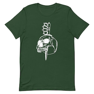 May include: A white graphic design on a dark green t-shirt featuring a skull with a knife and a brass knuckle weapon.