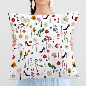 May include: White throw pillow with a floral pattern featuring red lips, high heels, and lipstick. The pattern is repeated throughout the pillow.