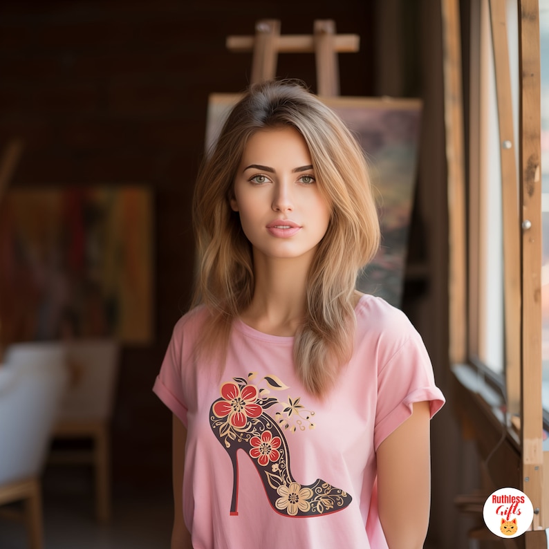 May include: A pink t-shirt featuring a black high-heeled shoe graphic. The shoe is decorated with red and gold floral designs.