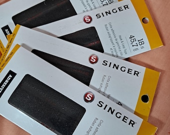 May include: Four packages of Singer brand hook and loop tape. Each package has a black strip of hook and loop tape, and the packaging is white with yellow accents. The packages are labeled with measurements of 18 inches and 45.7 cm.