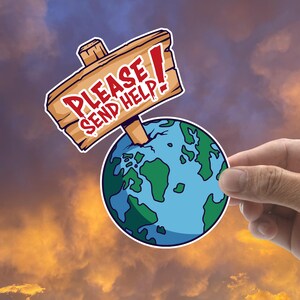 May include: A sticker featuring a cartoon Earth with green continents and blue oceans. A wooden sign with the words "PLEASE SEND HELP!" is attached to the Earth. The sticker is held by a hand against a sunset background.