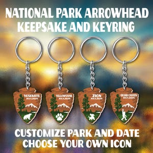 May include: Four keychains with arrowhead-shaped pendants. Each pendant features a different national park illustration, including Yosemite, Yellowstone, Zion, and Grand Canyon, with the text "JULY, 2025". The text "NATIONAL PARK ARROWHEAD KEEPSAKE AND KEYRING" is at the top, and "CUSTOMIZE PARK AND DATE CHOOSE YOUR OWN ICON" is at the bottom.