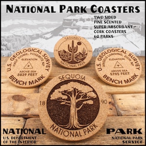 May include: Four round cork coasters with National Park designs. One coaster features a saguaro cactus, another a large tree, and two with U.S. Geological Survey logos. The coasters are pine-scented and absorbent, with text that reads "National Park Coasters."