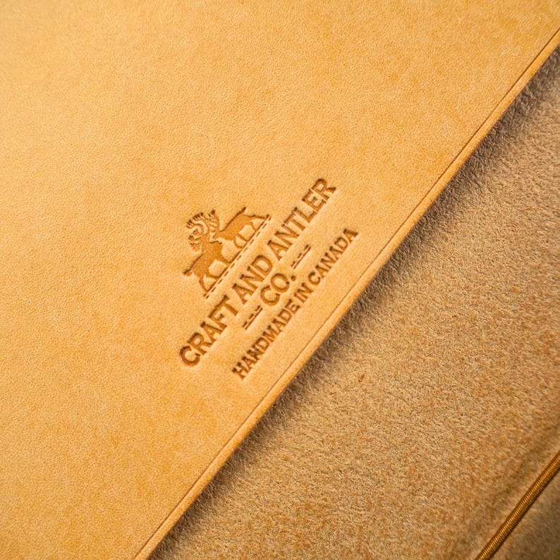 May include: Close-up of a tan leather surface with the text "CRAFT AND ANTLER CO." and "HANDMADE IN CANADA" embossed in the leather.