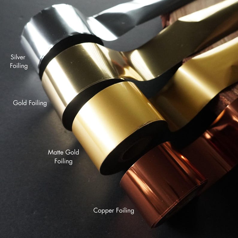 May include: Rolls of silver, gold, matte gold, and copper foil. The foil is on black spools.