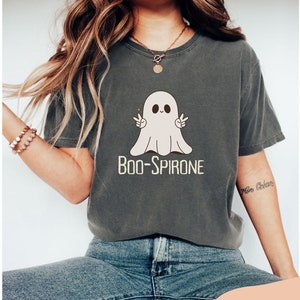 May include: A dark gray t-shirt with a cartoon ghost wearing a peace sign and the text "BOO-SPIRONE".