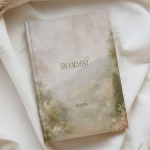 May include: A hardcover book with a matte finish featuring a soft, muted landscape painting of trees and foliage in shades of green, beige, and brown. The word "OFFICIANT" is printed in dark text above the date "8.19.26" centered on the cover.