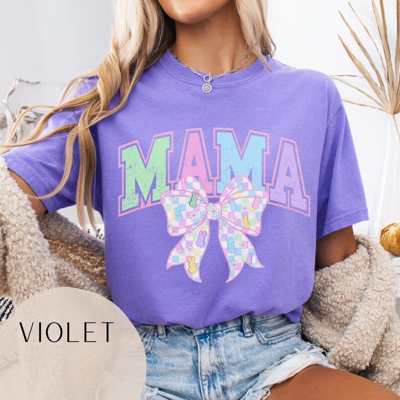 May include: A purple t-shirt with the word "MAMA" in rainbow colors and a pastel checkered bow with bunny and flower designs.
