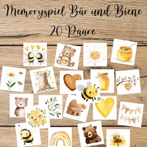 Puede incluir: Un juego de memoria con 20 pares de cartas que muestran ilustraciones de acuarela de abejas, osos, miel y flores. Las cartas están dispuestas sobre una superficie de madera, con el texto alemán "Memoryspiel Bär und Biene" en la parte superior.