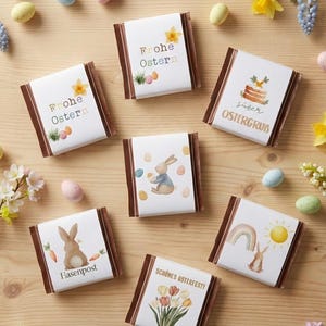 May include: An assortment of Easter-themed chocolate bars with white wrappers and brown edges. Each bar features a unique design, including bunnies, eggs, flowers, and German text. The bars are arranged on a wooden surface with scattered Easter eggs and flowers.