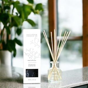 May include: White box with black text and a floral design, labeled "Davidson Candle Co. Reed Diffuser, infused with essential oils, 150 ml / 5 fl oz". A clear glass bottle with a black label that reads "Davidson Candle Co. Reed Diffuser" and a set of wooden reeds.