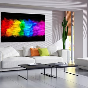 May include: A white couch with colorful throw pillows in a modern living room. A large abstract painting of a rainbow explosion hangs on the wall above the couch. Two black coffee tables are in front of the couch.