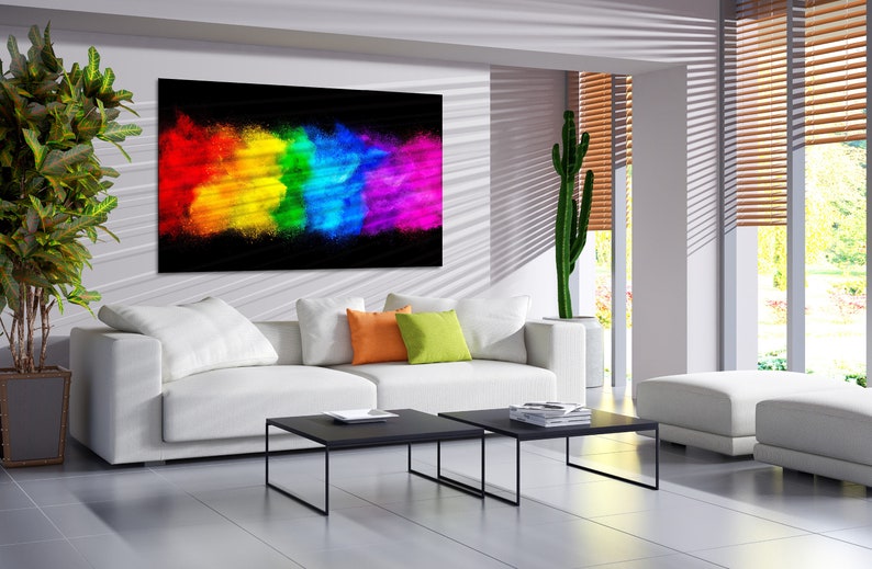 May include: A white couch with colorful throw pillows in a modern living room. A large abstract painting of a rainbow explosion hangs on the wall above the couch. Two black coffee tables are in front of the couch.