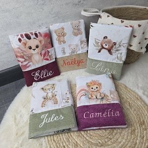 Puede incluir: Cinco estuches rectangulares de tela con ilustraciones de animales de dibujos animados, incluyendo leones y osos. Cada estuche tiene una base de pana de color sólido con un nombre bordado: Ellie, Naëlya, Lina, Jules y Camélia. Cierre a presión.