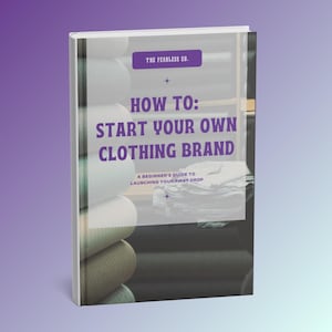 Può includere: Un libro con copertina rigida intitolato How To: Start Your Own Clothing Brand, A Beginner's Guide To Launching Your First Drop di The Fearless Co. La copertina presenta testo viola su un riquadro bianco, su uno sfondo di rotoli di tessuto.
