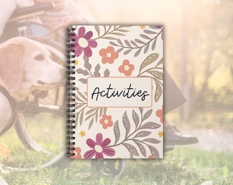 May include: A white spiral bound notebook with a floral pattern and the word "Activities" in a black frame. The flowers are pink, orange, and yellow.